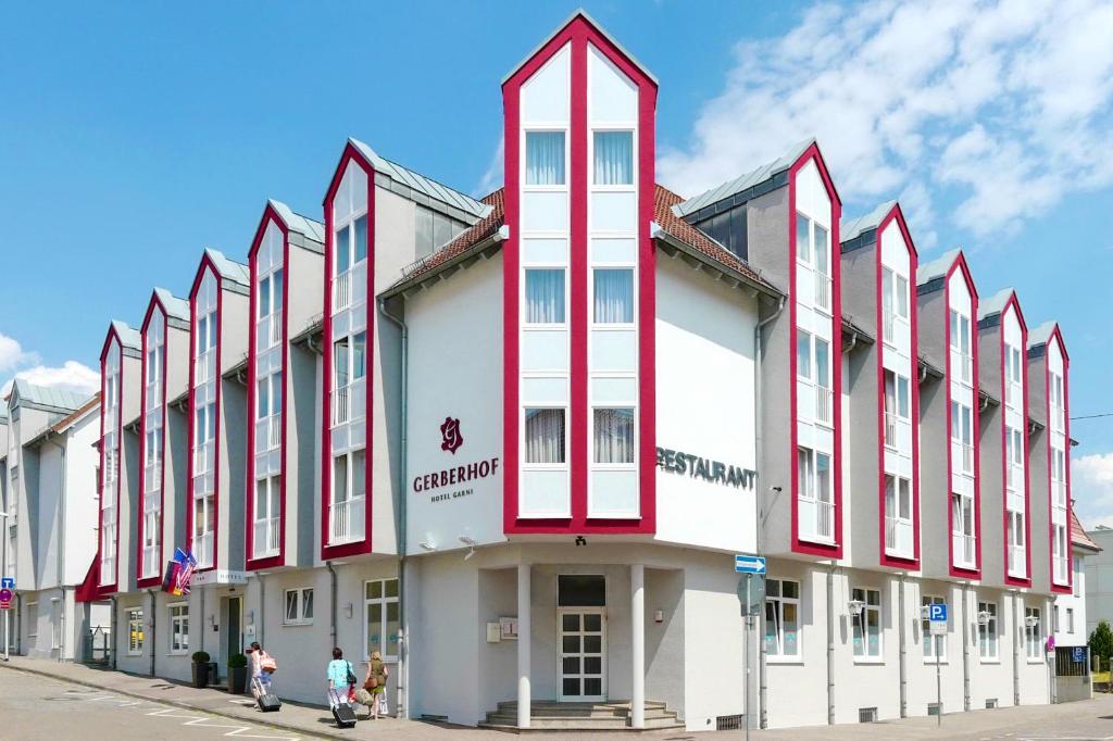 Un bâtiment rouge et blanc avec des personnes marchant devant lui dans l'établissement Hotel Gerberhof, à Backnang