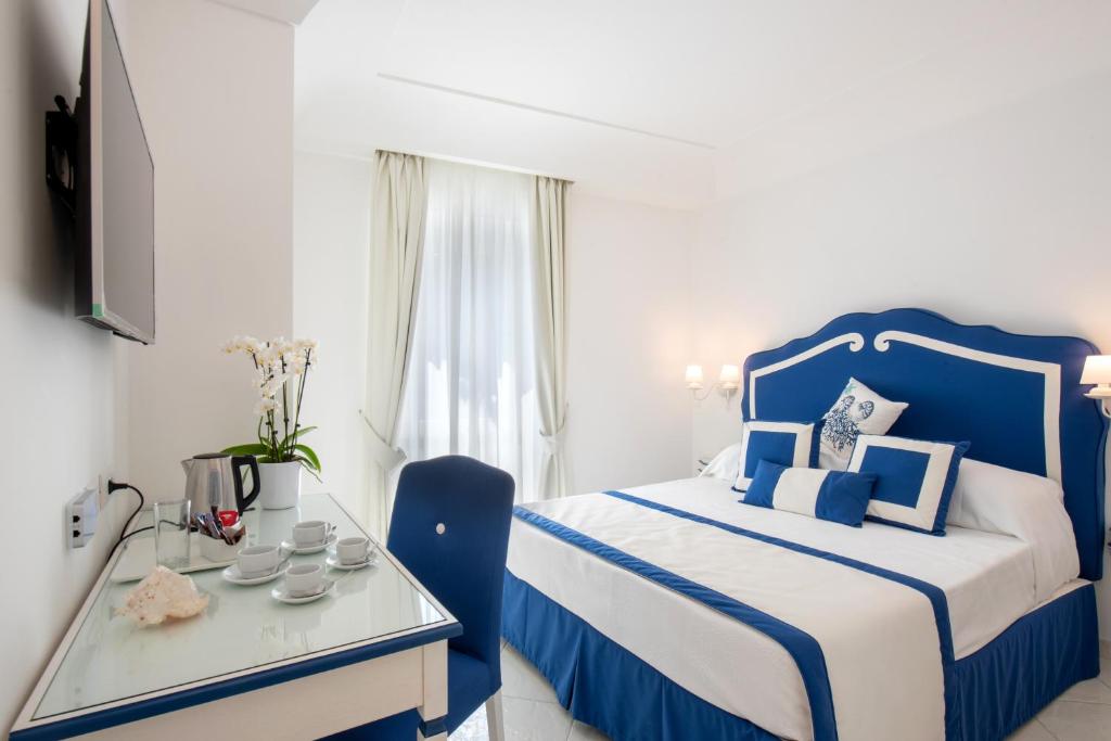 een blauwe en witte slaapkamer met een bed en een tafel bij Villa Viviani in Amalfi