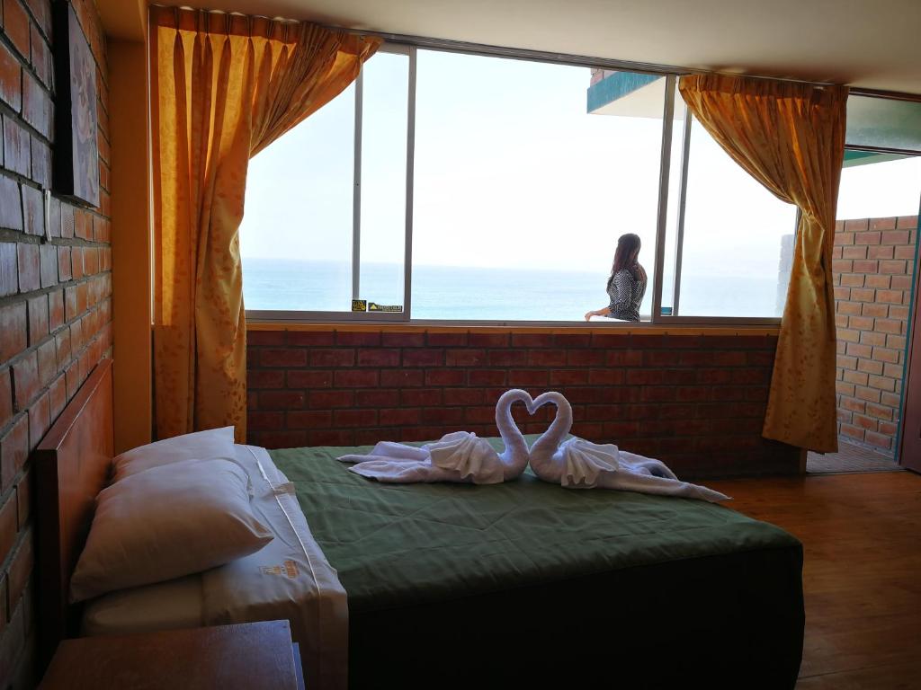 two swans sitting on a bed in front of a window at Meflo Playa Grande in Chala