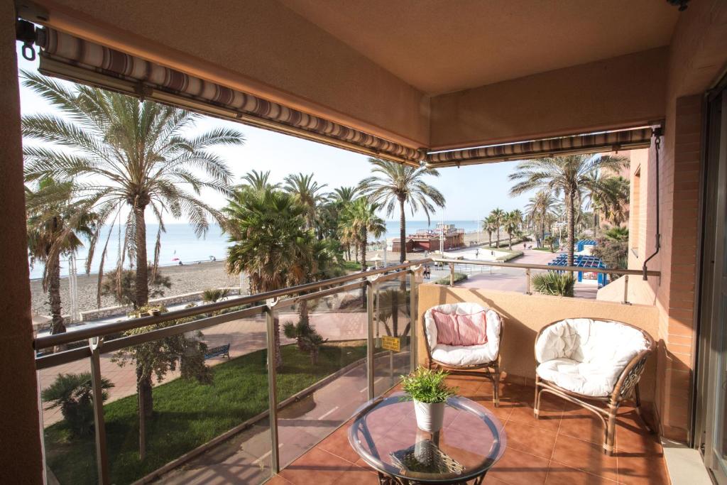 d'un balcon avec vue sur la plage et les palmiers. dans l'établissement Deluxe Playa Pacifico, à Malaga