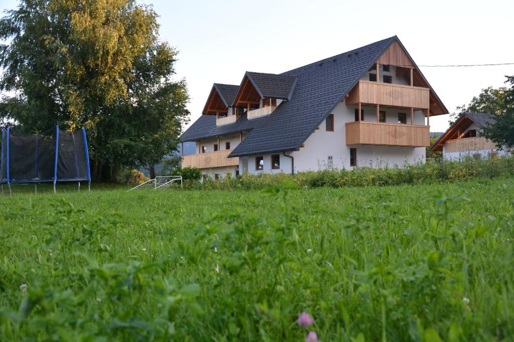 a white house with a black roof in a field at Pr' Koritnek in Bled