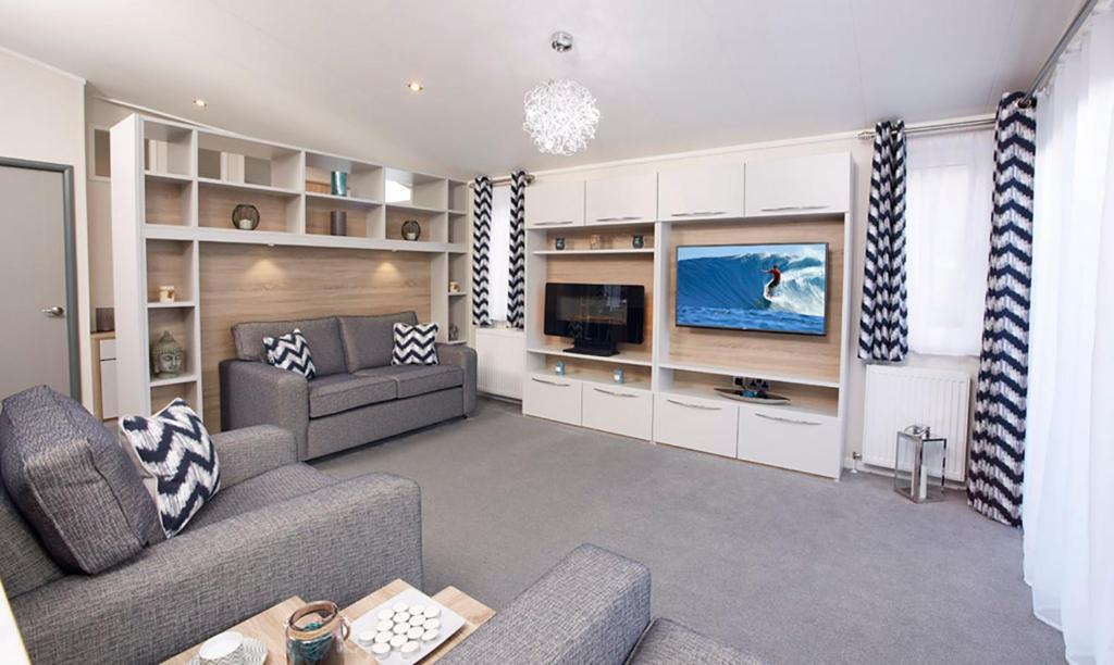 sala de estar con sofá y TV en New Forest Lodges Bashley Park, en New Milton