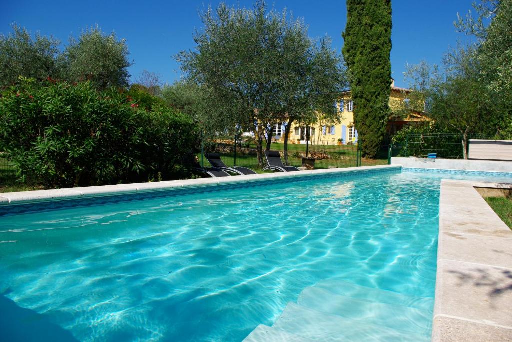 a swimming pool with blue water in a yard at Chambres d'Hôtes Carpe Diem in Callian