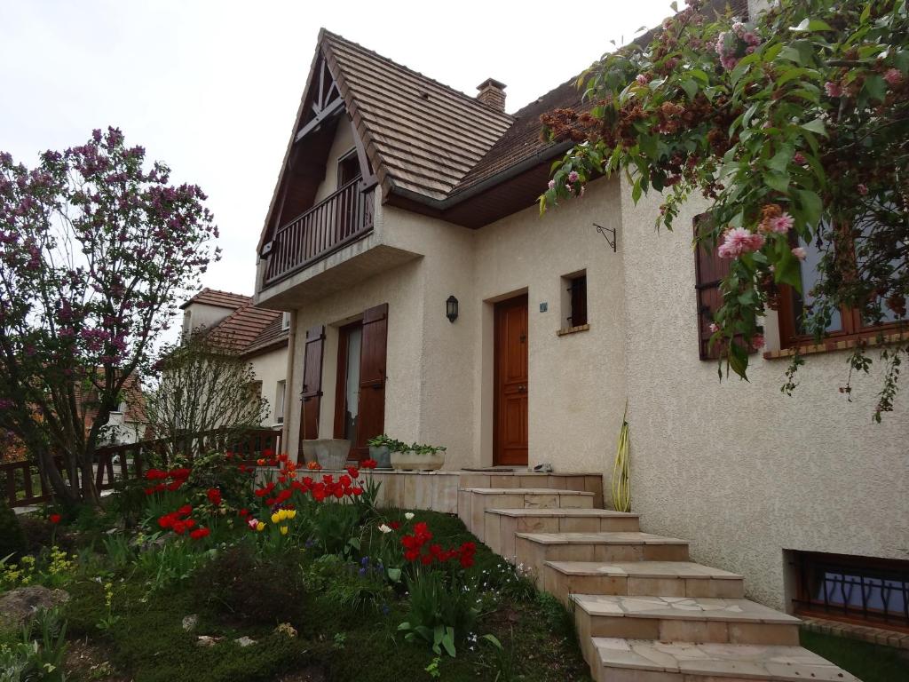 a house with stairs leading to a yard with flowers at 3 Chambres-Disneyland Paris in Saint-Thibault-des-Vignes