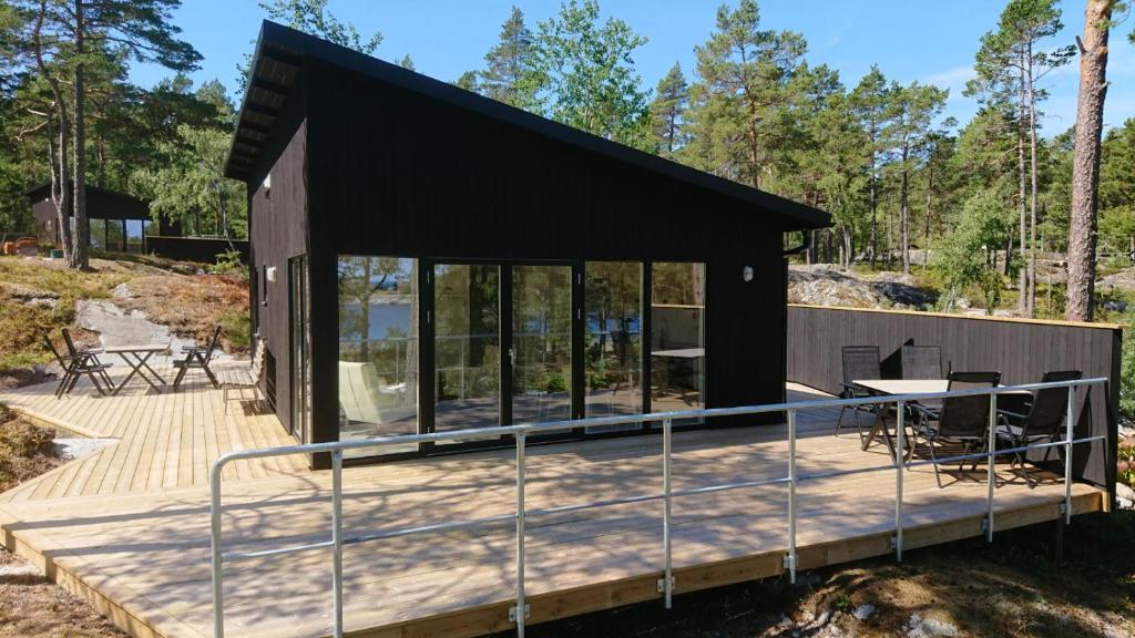 une maison avec un toit noir et une terrasse en bois dans l'établissement Kvarnsands Strandstugor / Kvarnsand Beach Lodges, à Grisslehamn