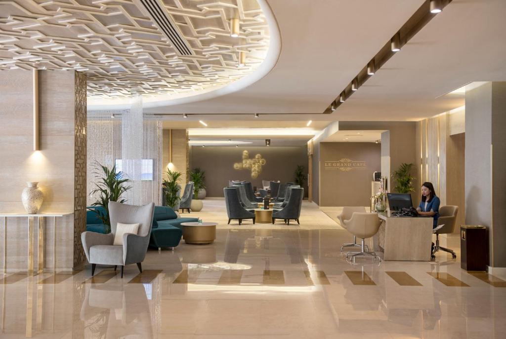 Two Seasons Hotel & Apartments في دبي: لوبي فندق فيه امرأة تجلس في مكتب