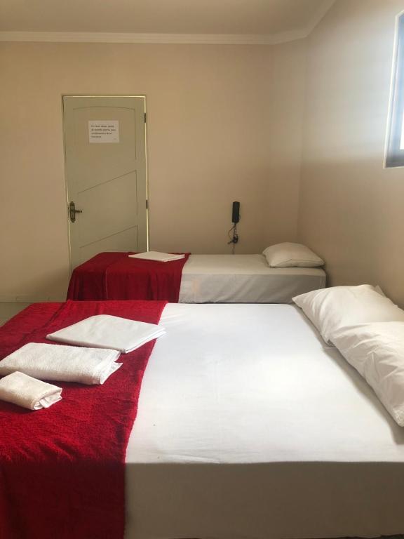 two beds in a room with red blanket and white sheets at Prime Hotel in Caruaru