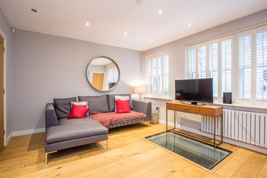 a living room with a couch and a mirror at The Escalier Mews - Bright 3BDR Home in London