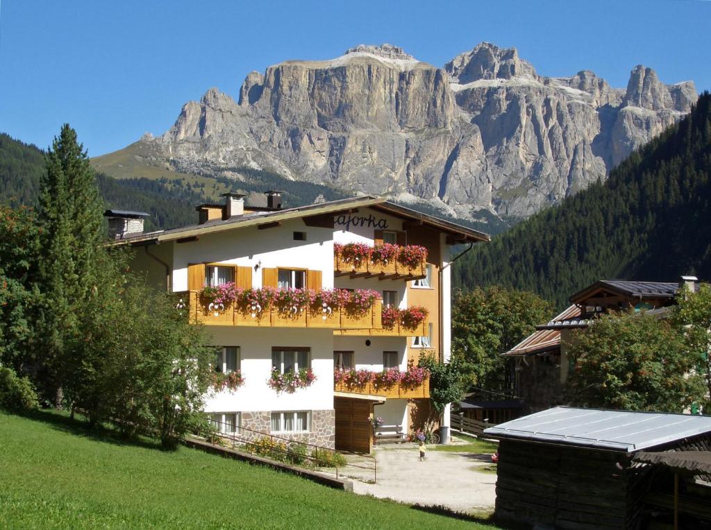 un bâtiment avec des fleurs devant une montagne dans l'établissement Albergo Majorka, à Canazei