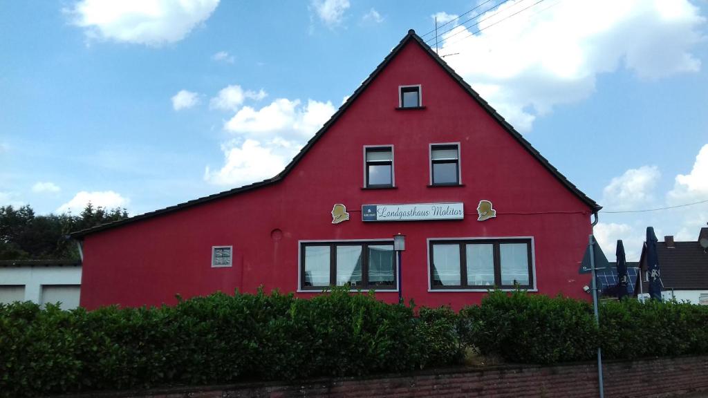 una casa roja con un cartel en el costado. en Gaststätte Molitor, en Saarlouis