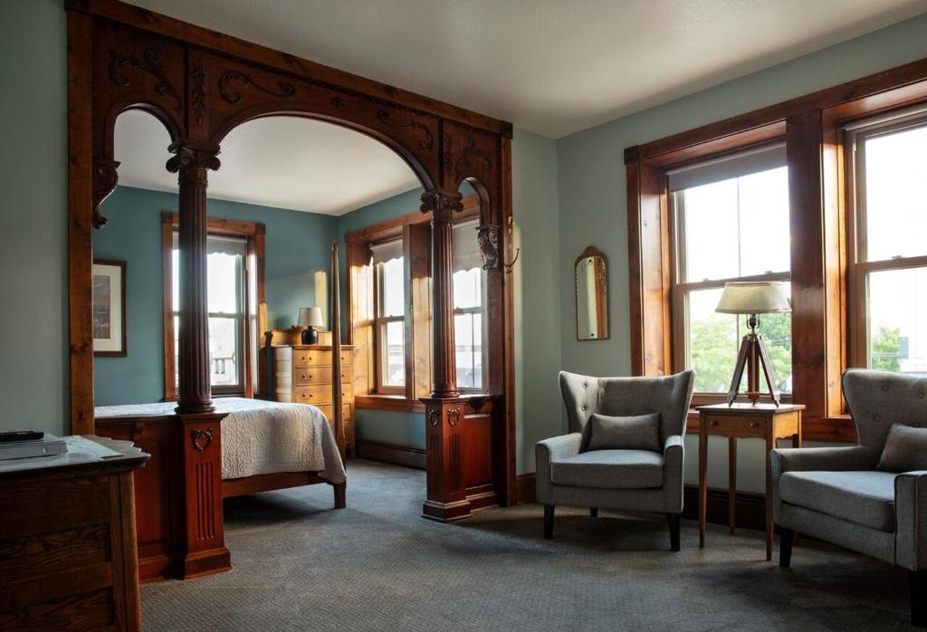 a bedroom with a bed and a chair and a mirror at Inn at Cedar Crossing in Sturgeon Bay