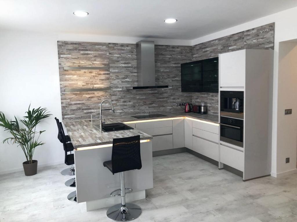 a kitchen with white cabinets and a stone wall at Luxusní apartmán přímo v centru u hotelu Thermal in Karlovy Vary