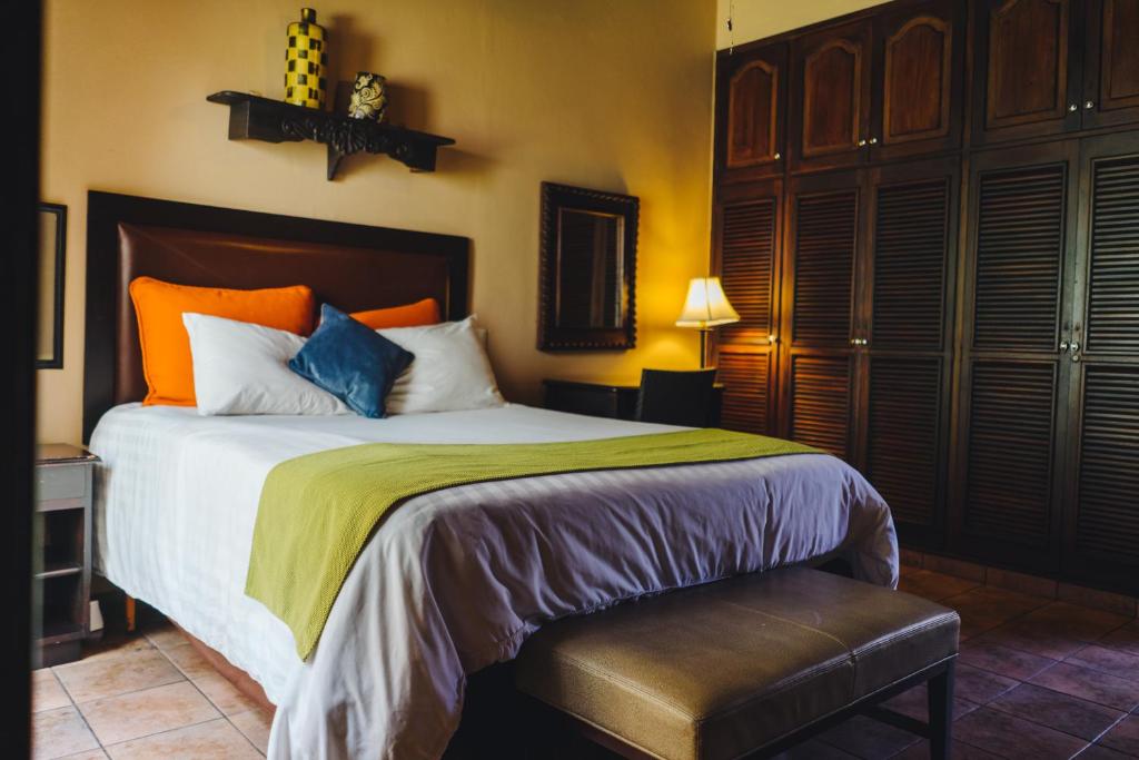 a bedroom with a large bed with orange and blue pillows at Humuya Inn in Tegucigalpa