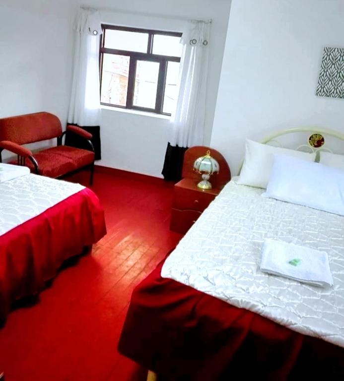 una camera con due letti e una sedia e una finestra di Cuzco Central Hostel a Cuzco