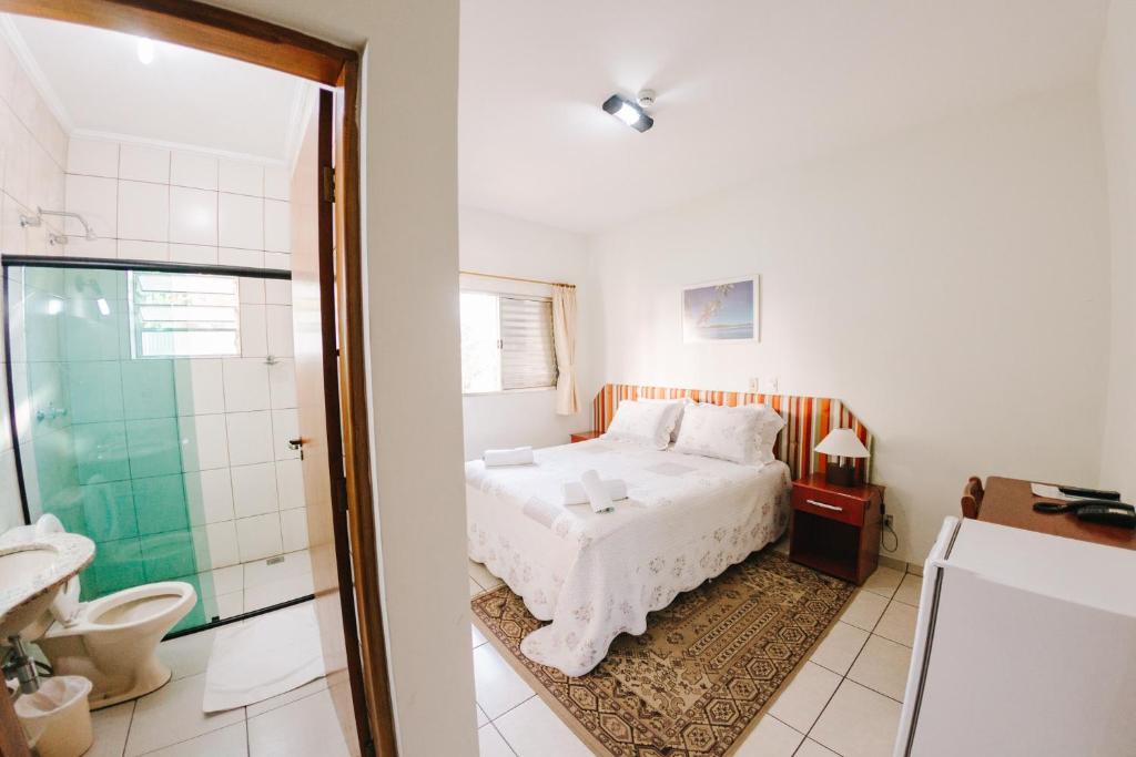 a bedroom with a bed and a bathroom with a shower at Hotel Passaledo in Indaiatuba