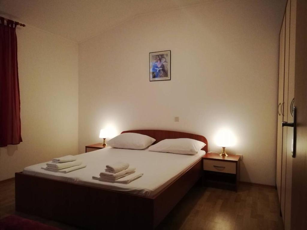1 dormitorio con 1 cama con 2 lámparas y toallas en Apartments Čepo, en Makarska