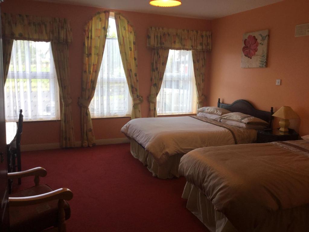 a hotel room with two beds and two windows at Colonelwood House in Westport