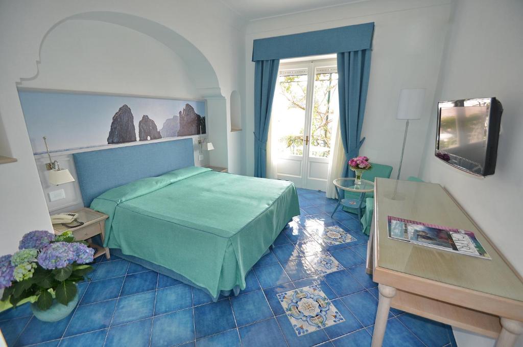 una camera con letto verde e finestra di Albergo Gatto Bianco a Capri
