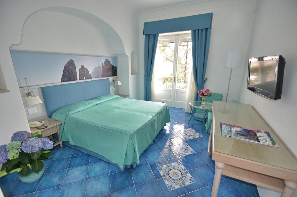 a bedroom with a green bed and a window at Albergo Gatto Bianco in Capri