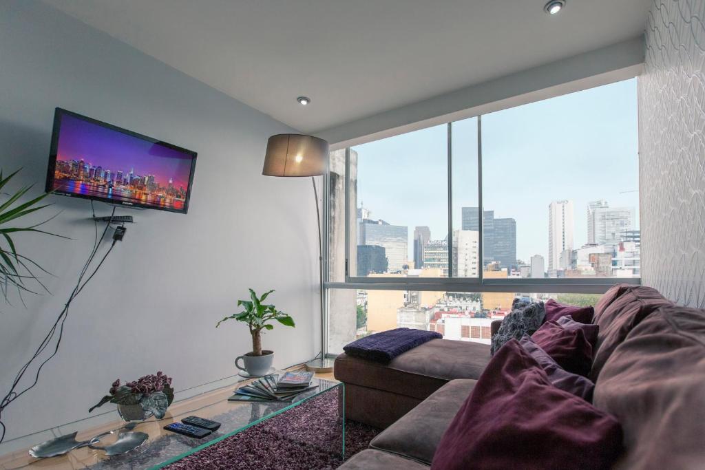 a living room with a couch and a large window at Immaculate Chapultepec Apartment in Mexico City