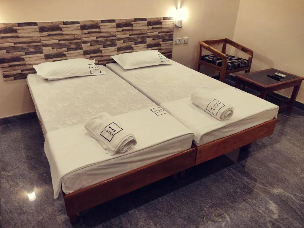 a bedroom with two beds in a room with a table at Hotel Wins in Kanyakumari