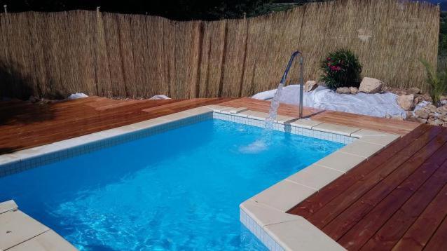 a swimming pool in a backyard with a wooden fence at L'Auberge du Mazet in Lodève