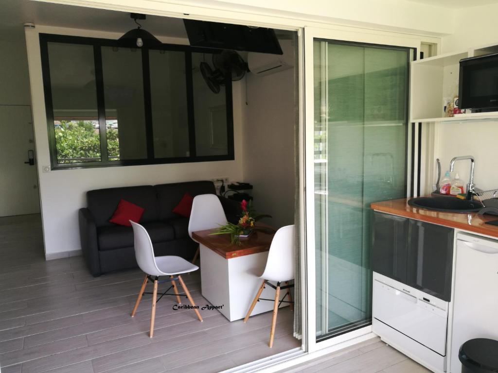 a kitchen and living room with a couch and chairs at Caribbean Appart' in Le Moule