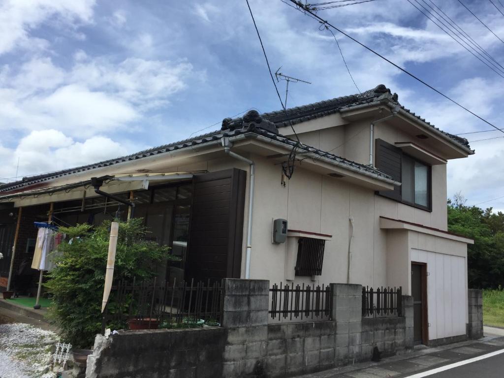 una pequeña casa blanca con una valla delante en Ibusiki Shizuka en Ibusuki