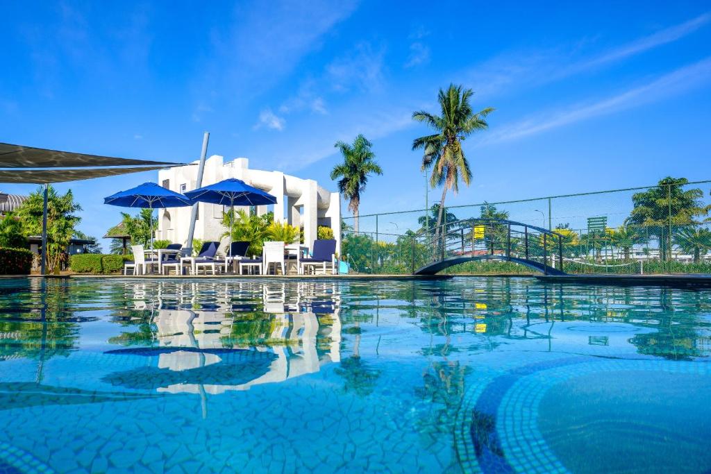 a pool with chairs and umbrellas in front of a building at Fiji Gateway Hotel in Nadi