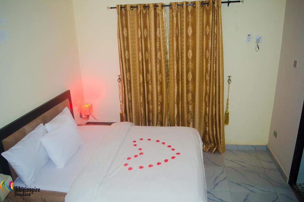 Una cama blanca con una decoración de corazón rojo. en Pentagon Hotel and Suites, en Umueme