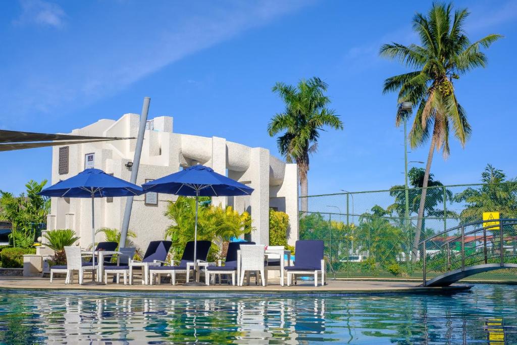 a pool with chairs and umbrellas next to a building at Fiji Gateway Hotel in Nadi