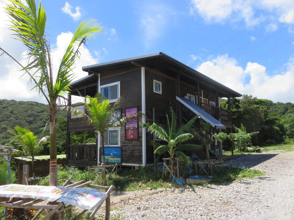 a black house with palm trees in front of it at Okinawa Freedom in Nakijin