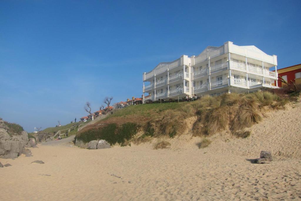 um edifício no topo de uma colina ao lado de uma praia em Hotel Pineda Playa em Noja