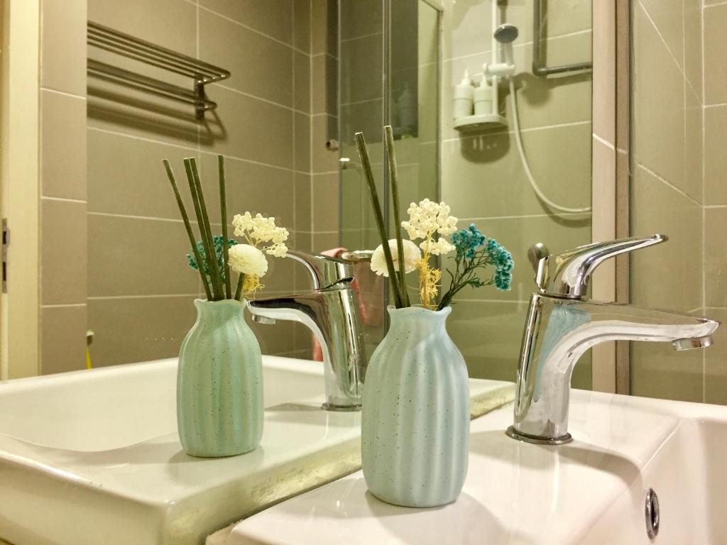 zwei Vasen mit Blumen auf einem Waschbecken in der Unterkunft Splendid Suite 2 Bedroom @ Sunway & PJ in Petaling Jaya