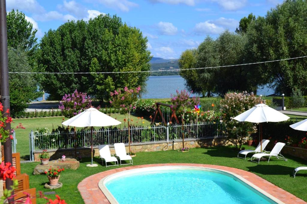 una piscina con sedie, ombrelloni e acqua di Appartamenti La Rosetta a Magione