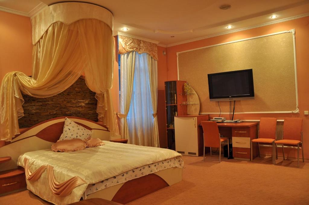 een slaapkamer met een bed, een bureau en een televisie bij Focus Hotel in Khust