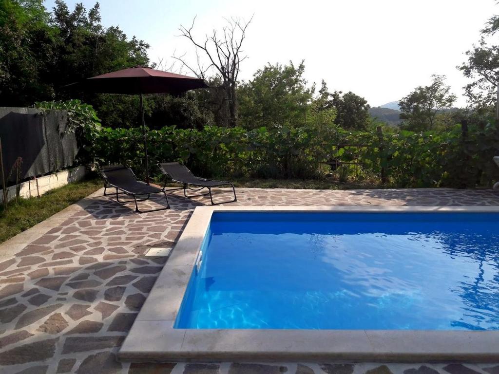 - une piscine avec 2 chaises et un parasol dans l'établissement Apartment Nada with Private Pool, à Buzet