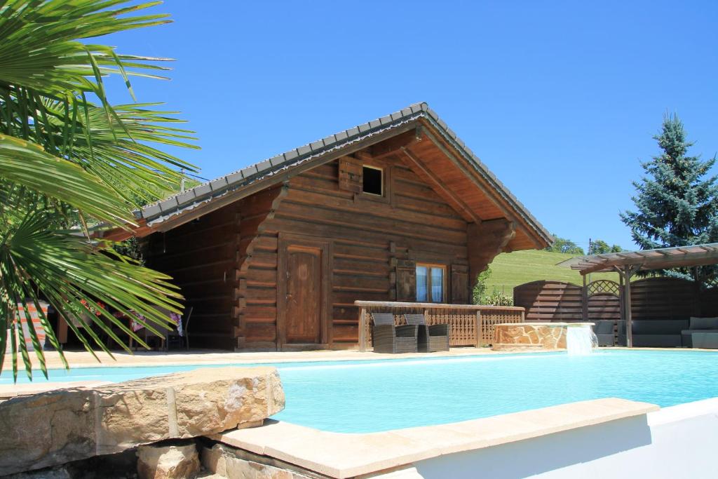 a log cabin with a swimming pool in front of a house at Chalet le Pré de la Dame in Épagny