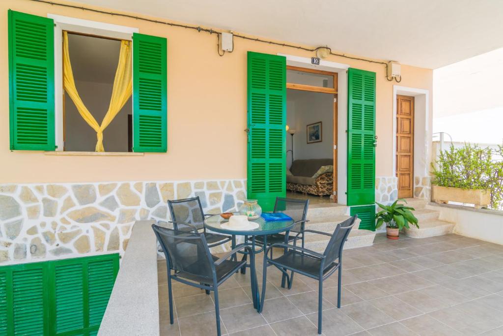a patio with a table and chairs and green shutters at Casa Tradicional Can Picafort in Can Picafort