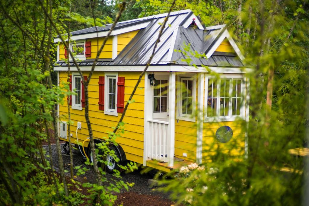 une petite maison jaune assise dans les bois dans l'établissement Mount Hood Village Savannah Tiny House 4, à Welches