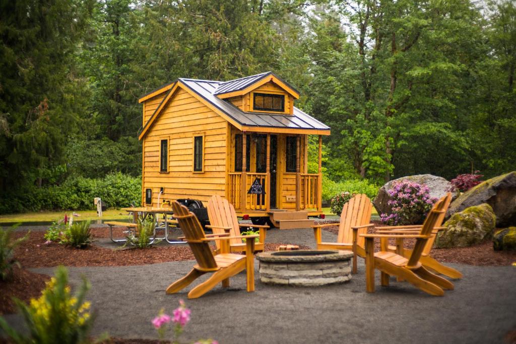 eine Holzhütte mit Stühlen, einem Tisch und einem Kamin in der Unterkunft Mount Hood Village Atticus Tiny House 8 in Welches