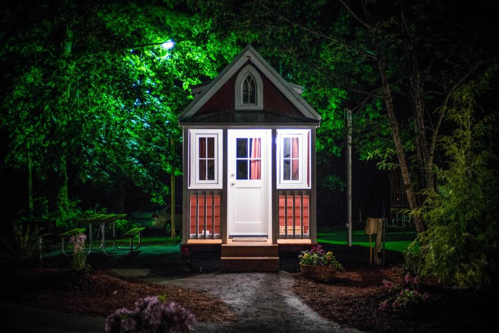 une petite maison avec une porte blanche dans un jardin la nuit dans l'établissement Mount Hood Village Scarlett Tiny House 3, à Welches