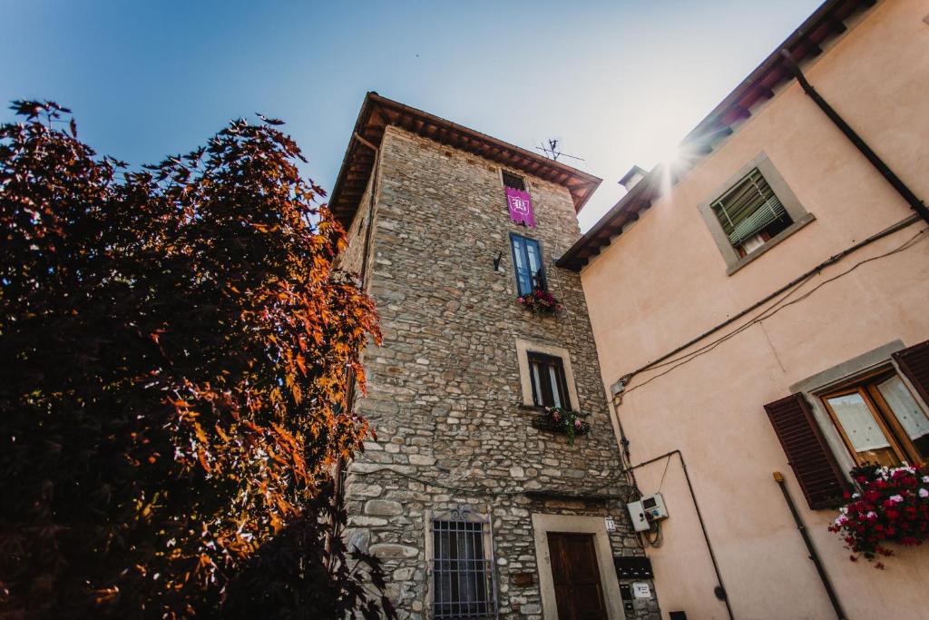 een hoog stenen gebouw met een boom ernaast bij La Torre del Vicario in Palazzuolo sul Senio