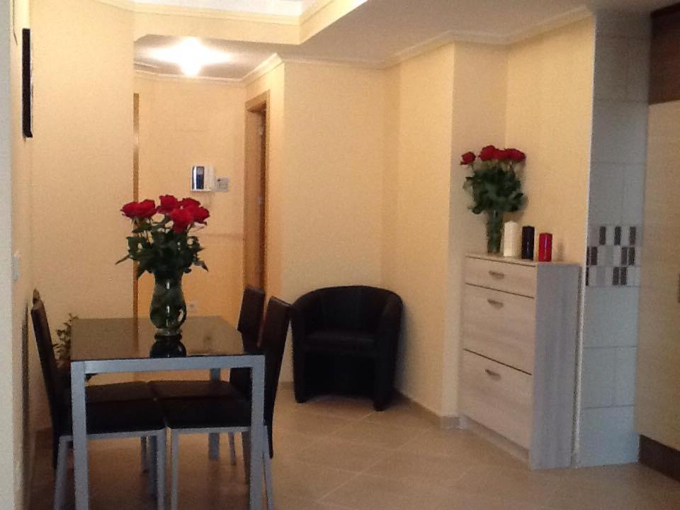 een eetkamer met een tafel met een vaas van rode rozen bij Apartment Costa Formentera in Formentera de Segura