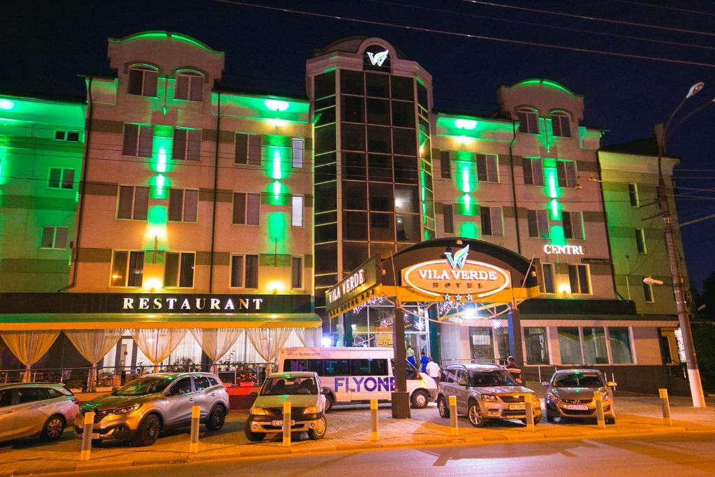 un grand bâtiment avec des voitures garées devant lui dans l'établissement Vila Verde, à Chişinău