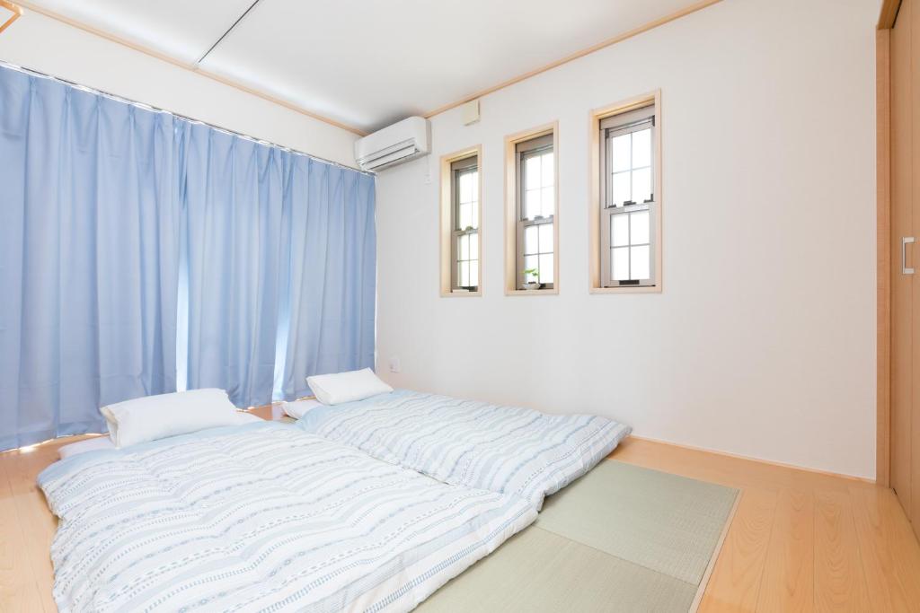 een bed in een kamer met blauwe gordijnen bij JIYUKA INN in Izumi-Sano