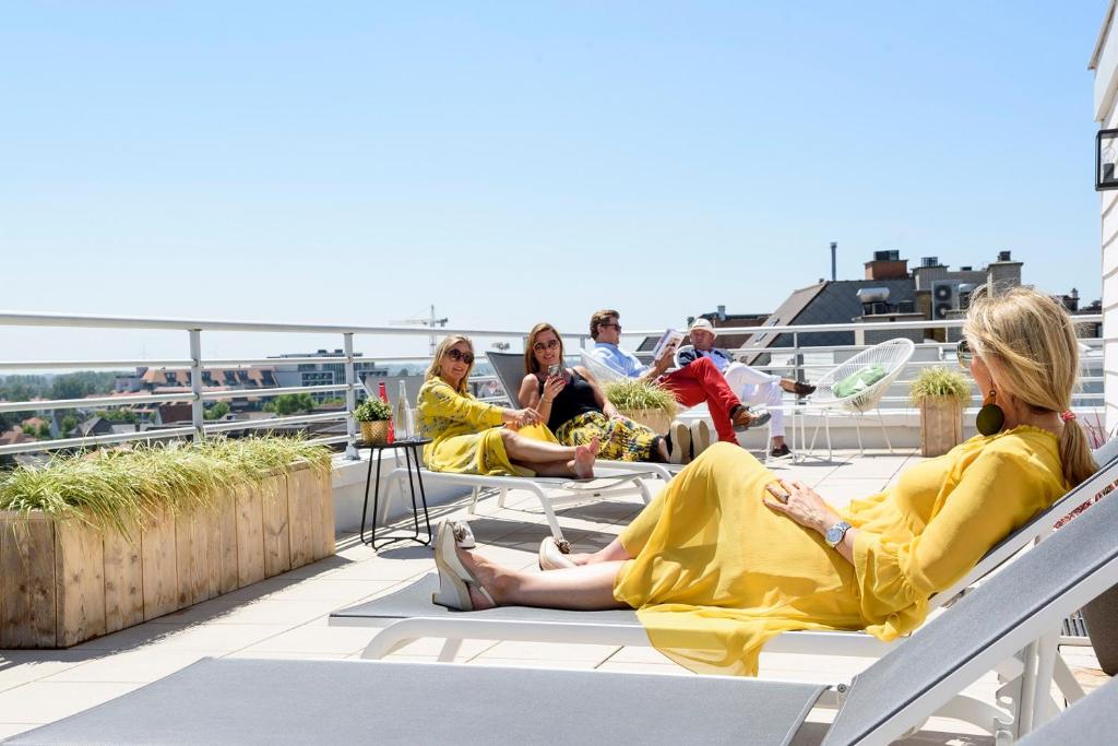 un grupo de mujeres sentadas en el techo de un edificio en Hotel Nelson en Knokke-Heist