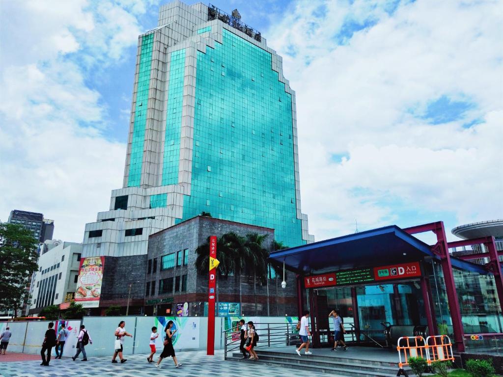 Un groupe de personnes marchant devant un grand bâtiment dans l'établissement Guangzhou New Century Hotel, à Huadu