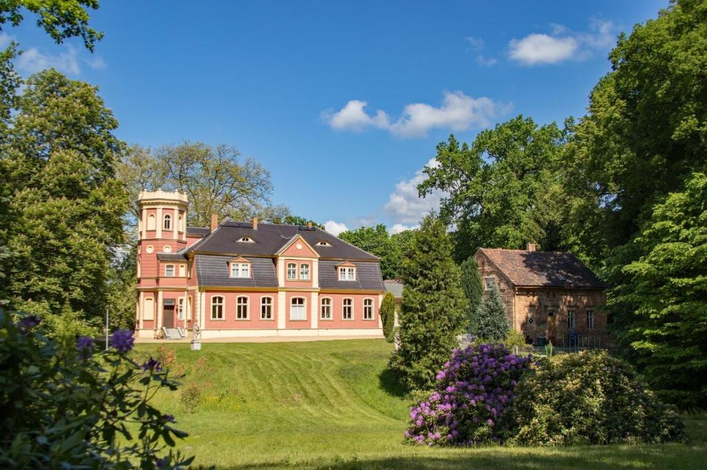 a large house on a grassy hill with a barn at Ferienwohnung "Schloss Kromlau" in Kromlau