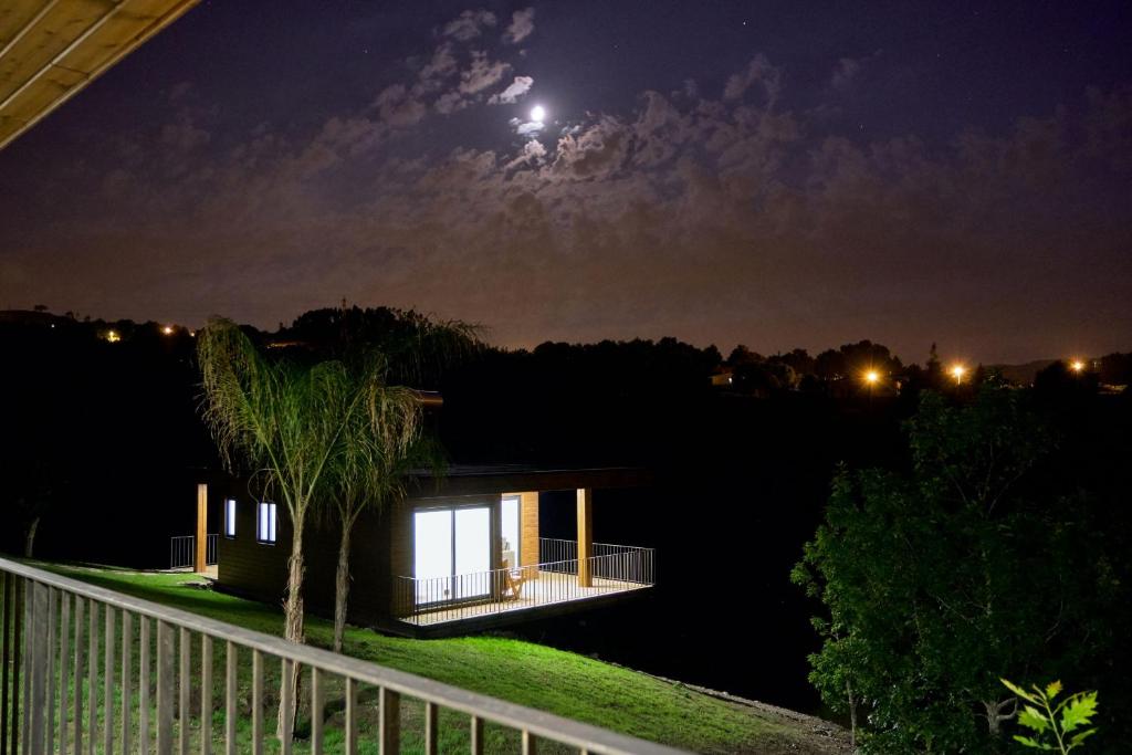 une maison la nuit avec la lune dans le ciel dans l'établissement Quinta de Silharezes, Lda, à Ponte da Barca